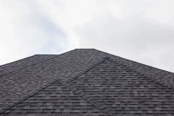 Close-up view of an asphalt shingle roof showing intersecting roof lines and installed roofing materials