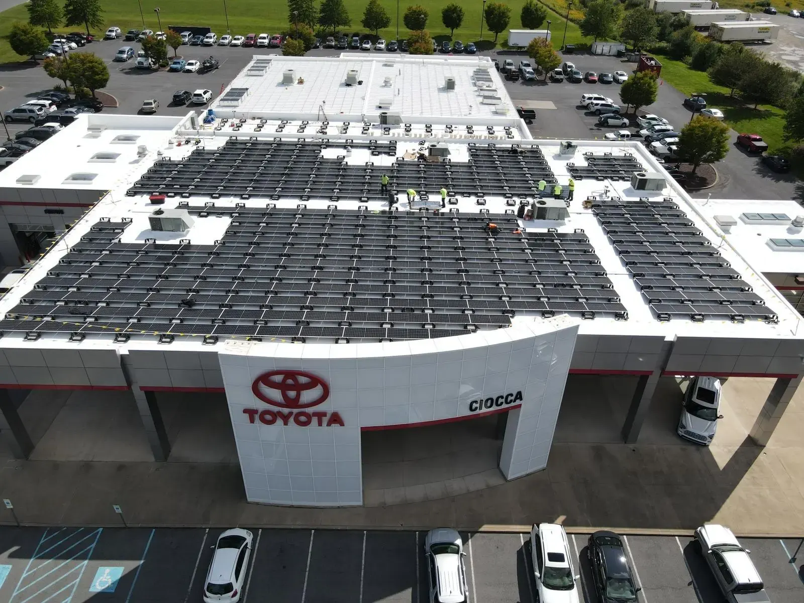 Installation crew setting solar panels on a dealership roof