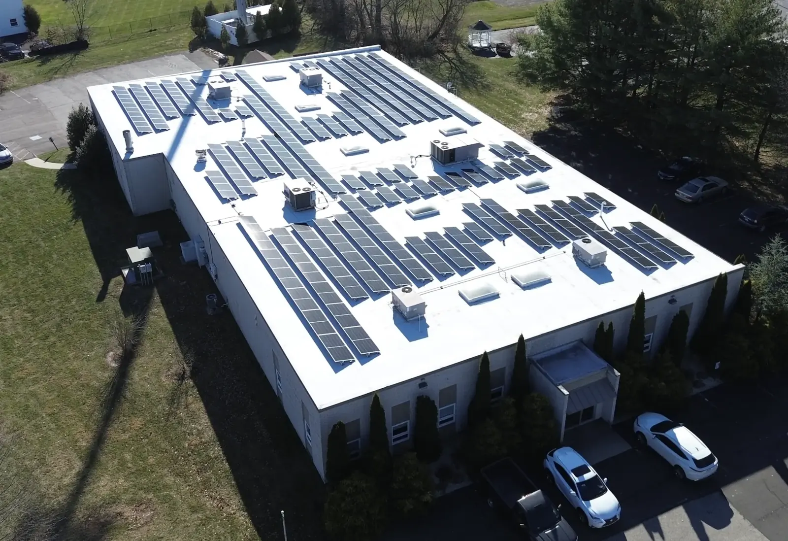 Aerial view of a commercial building with a full rooftop solar array installed on a white membrane roof